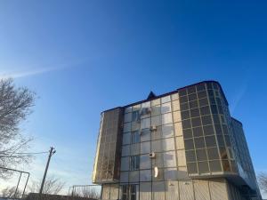 un edificio de cristal alto con un cielo azul en el fondo en Уютная и просторная 3х комнатная в ЦЕНТРЕ, en Uralsk