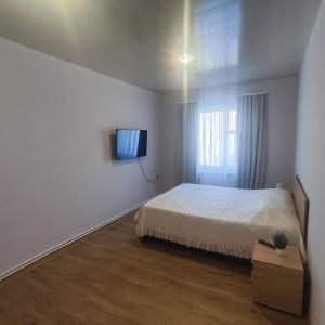 1 dormitorio con 1 cama y TV en la pared en LANJ IN Eco Garden/ Guest House, en Nurrnus