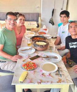 Un groupe de personnes assises autour d'une table avec de la nourriture dans l'établissement Nefertarie Guest House, à Louxor