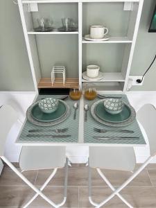 eine Küche mit einem Tisch mit 2 Stühlen und Tellern in der Unterkunft Magnifique Studio à 30 min de La Défense in Conflans-Sainte-Honorine