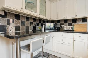 a kitchen with white cabinets and black tiles at Chester Greenway House - Ideal 1 Bedroom Home, EV Charger & Parking - Sleeps 4 in Chester