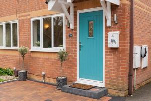 a blue door on the side of a brick house at Chester Greenway House - Ideal 1 Bedroom Home, EV Charger & Parking - Sleeps 4 in Chester