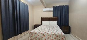 1 dormitorio con 1 cama con cortinas azules en Discovery Beach Apartments, en Aguada