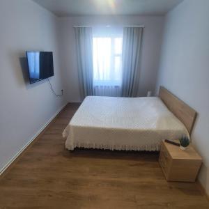 1 dormitorio con 1 cama y TV en la pared en LANJ IN Eco Garden/ Guest House, en Nurrnus