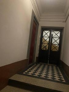a hallway with a black door and a checkered floor at Апартаменти на вулиці Залізняка - бічна вулиці Антоновича in Lviv +8 photos