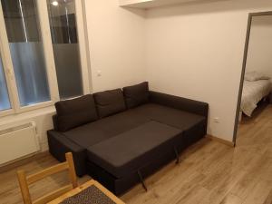 ein schwarzes Sofa im Wohnzimmer mit Spiegel in der Unterkunft Appartement T2 privé proche gare in Marseille