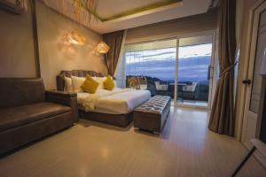 a bedroom with a bed and a couch and a window at Kirin Sky Resort in Khao Kho