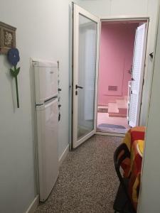 une cuisine avec un réfrigérateur et une porte menant à une chambre. dans l'établissement B&B Domus Oriens - monolocale indipendente in villa, à Portoscuso