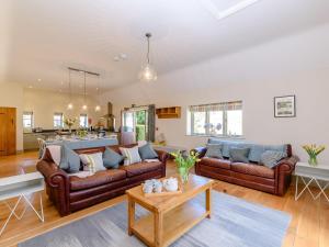 a living room with brown leather couches and a table at Tull in Dyrham