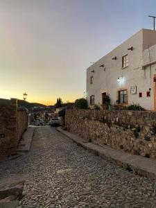 una calle de piedra con un edificio y una pared en Alex, en Real de Catorce