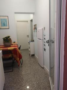 uma cozinha com uma mesa e um frigorífico branco em B&B Domus Oriens - monolocale indipendente in villa em Portoscuso