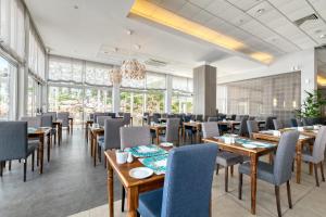 un restaurant avec des tables et des chaises en bois ainsi que des fenêtres dans l'établissement Atlantica Sea Breeze, Adults Only, à Protaras