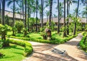 a garden with palm trees and a walkway at Suite Hotel Apartment Legian by RCP in Seminyak