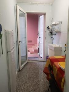 ポルトスクーゾにあるB&B Domus Oriens - monolocale indipendente in villaのピンクのバスルームにつながるドア付きの部屋