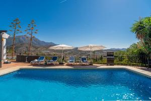- une piscine avec des chaises longues et des parasols dans l'établissement Villa Maroma, à Viñuela