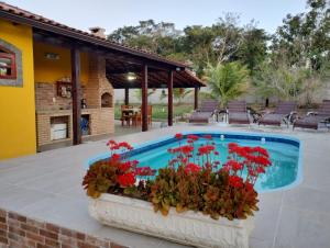 a pool with red flowers in a planter next to a house at Pouso Zen in Araruama