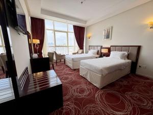 a hotel room with two beds and a large window at Al Rayyan Towers 2 in Makkah