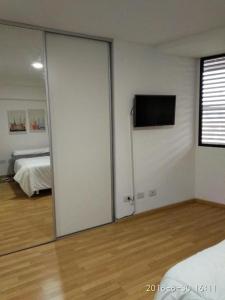 1 dormitorio con puerta corredera y TV en la pared en Alojamiento del Boulevard en Rosario