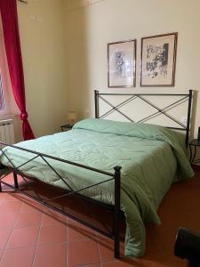 a bedroom with a green bed with two pictures on the wall at L'orologio matto in Marina di Carrara