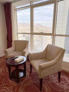 two chairs and a table in a room with a large window at Al Rayyan Towers 2 in Makkah