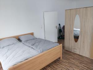Schlafzimmer mit einem Bett mit einem Holzrahmen und einem Spiegel in der Unterkunft 3 Zimmer Monteurwohnung 1 Etage in Riedstadt