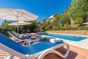 een zwembad met stoelen en parasols naast een zwembad bij Villa Maroma in Viñuela