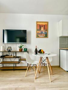 a white table and chairs in a kitchen with a tv at Cosy Stay Muranów in Warsaw