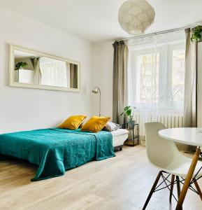 a bedroom with a bed with a blue blanket and a table at Cosy Stay Muranów in Warsaw