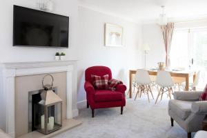 Central Chichester 3bd Mews House For Up To 6 في شيشستر: غرفة معيشة مع كرسي احمر ومدفأة