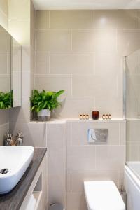 a bathroom with a sink and a toilet and a tub at Central Chichester 3bd Mews House For Up To 6 in Chichester