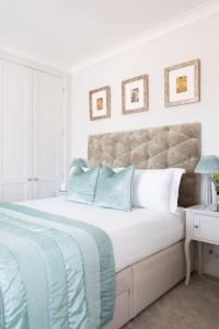 a white bedroom with a large bed with blue pillows at Central Chichester 3bd Mews House For Up To 6 in Chichester