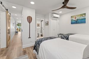 Un dormitorio blanco con dos camas y un ventilador de techo. en Fully Remodeled Ocean Front Comfort HKOK316, en Kihei