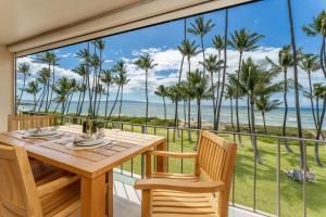 Una mesa y sillas en un balcón con vista al mar. en Fully Remodeled Ocean Front Comfort HKOK316, en Kihei