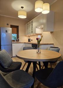 une cuisine avec une table et des chaises avec un vase de fleurs dans l'établissement Dom nad jeziorem Morenowe Wzgórze, à Płociczno