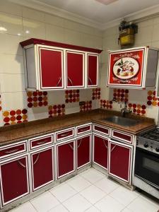 a kitchen with red cabinets and a sink at اطلالة السحر والجمال in Alexandria