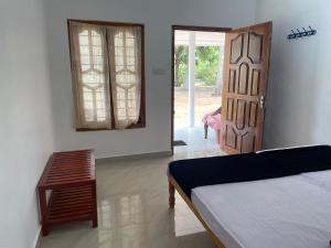 um quarto com uma cama, uma porta e uma mesa em Gopalapuram Guest House em Nilaveli