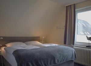 a bed in a room with a large window at Haus Triton in Büsum