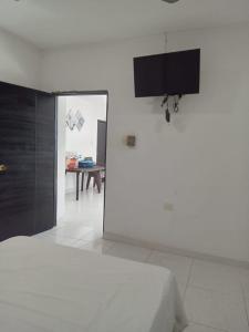 a white room with a bed and a tv at HOTEL MI RANCHITO in Sincelejo