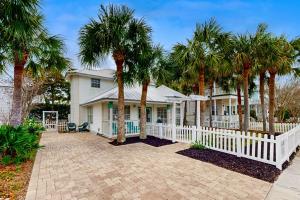a white fence in front of a house with palm trees at Cottages of Crystal Beach Sea La Vie in Destin