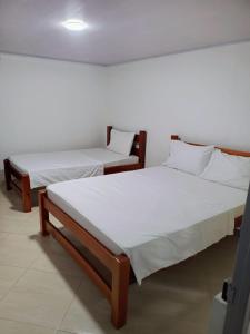two beds in a room with white sheets at Hotel Zarina in Villavicencio