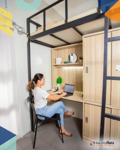 a woman sitting at a desk in a loft bed at The Flats Amorsolo in Manila