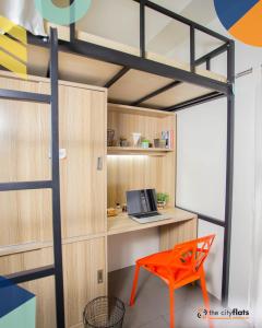 a loft bed in a room with a desk and a laptop at The Flats Amorsolo in Manila