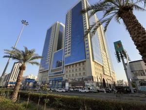 a large building with palm trees in front of a street at Al Rayyan Towers 2 in Makkah