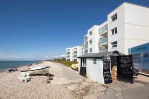 a building on a beach with a boat on the shore at High-End Beachfront Getaway Sea View King Bed in East Wittering