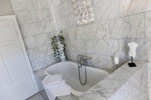 y baño con bañera y paredes de mármol. en Exklusives Landhaus in den Bergen, en Arzl im Pitztal