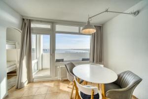 d'une salle à manger avec une table, des chaises et une fenêtre. dans l'établissement Ferienpark - Haus E, App 0E0903, à Heiligenhafen