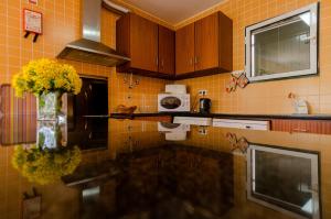 uma cozinha de azulejos amarelos com um vaso de flores amarelas em WelcomeBuddy - Casa dos Avós - Garden & Lake II em Sete Cidades