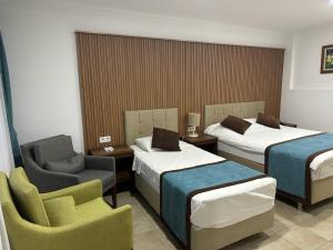 a hotel room with two beds and a chair at Dinc Pension in Bodrum City