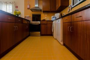 a kitchen with wooden cabinets and an orange tiled floor at WelcomeBuddy - Casa dos Avós - Garden & Lake II in Sete Cidades