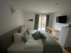 - une chambre avec un grand canapé blanc et des oreillers dans l'établissement Ferienwohnung Gschwendt, à Miesbach